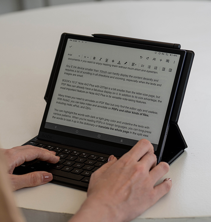 Zdjęcie ukazuje tablet Onyx Boox Tab Ultra, który oparty jest na Android 11. Na zdjęciu widać również ręce, które pracują z tekstem. Pisanie tekstu w biurze.