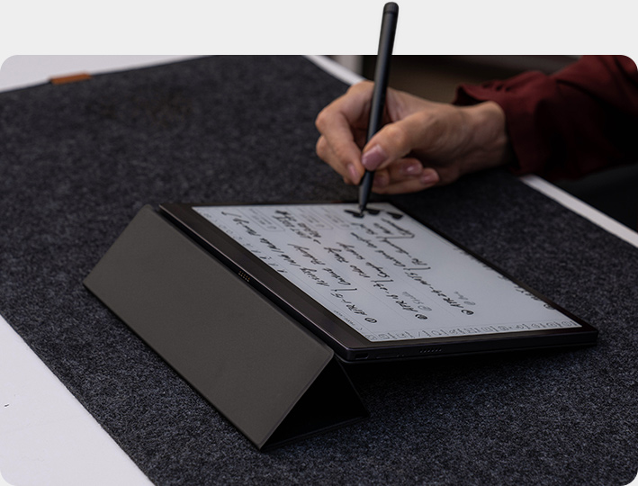 Zdjęcie przedstawia Onyx Boox Tab Ultra tablet z androidem 11, który posiada ekran E Ink. Leży on na czarnej podstawce.
