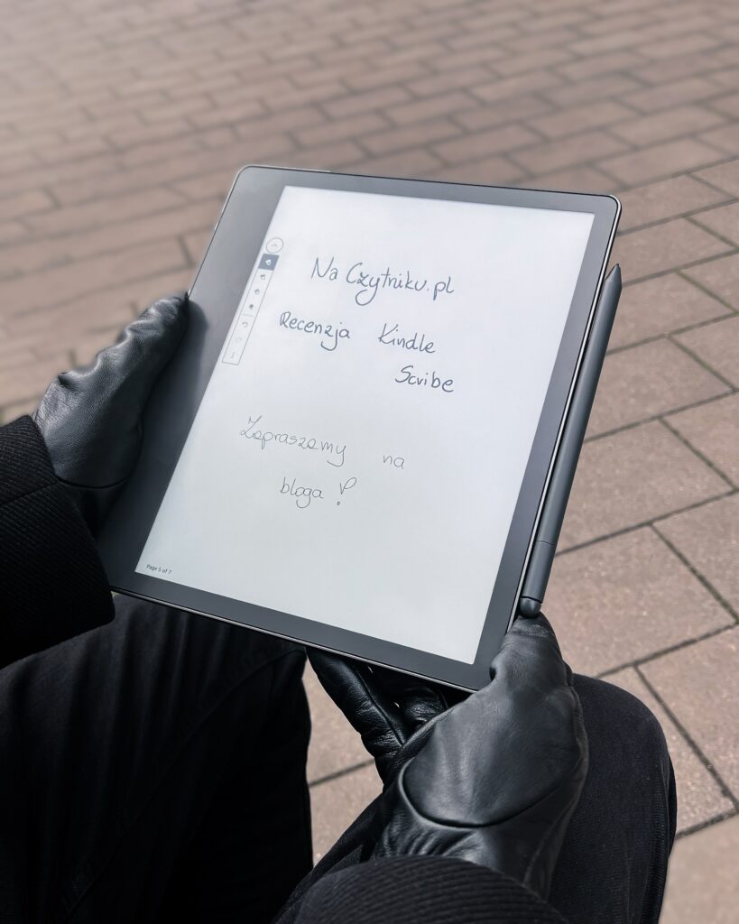 Kindle Scribe na zewnątrz. Na czytniku wyświetla się napis naczytniku.pl