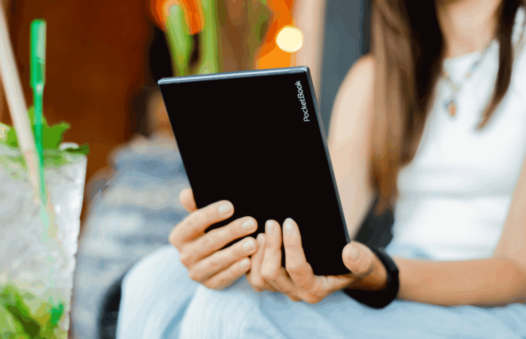 Czytnik e-book marki PocketBook trzymany w rękach przez kobietę