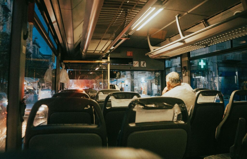 Autobus po zmroku, którego ciepłe światła odbijają się w szybach.